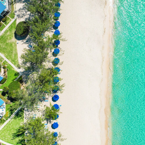 Seven Mile beach from above with white sands and trees and roofs of resort