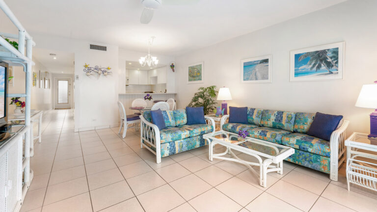 Living and dining room of ground floor Villa 3 with tiled floors looking toward kitchen in Grand Cayman Condo Rental.