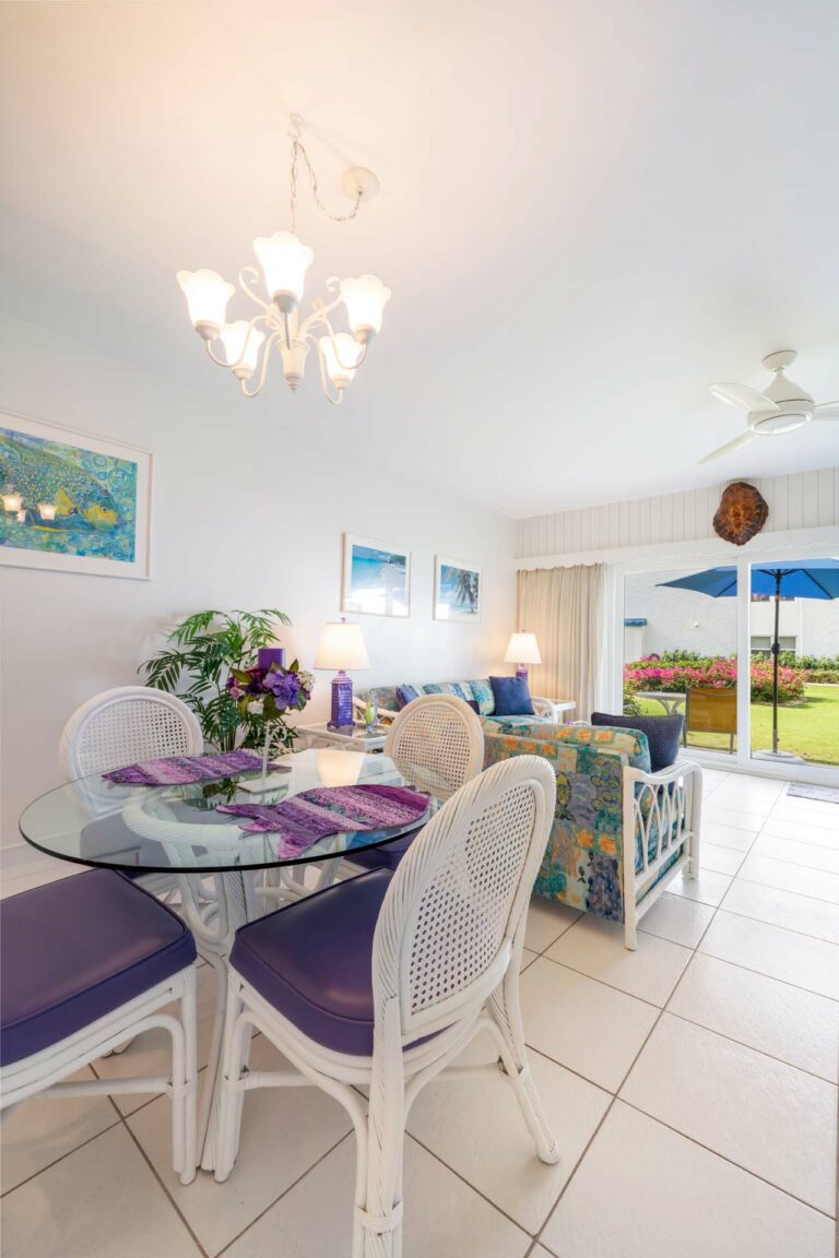 View of living and dining area in Villa 3, Seven Mile Beach Condo Rental, showcasing the gardens and patio from the first floor."