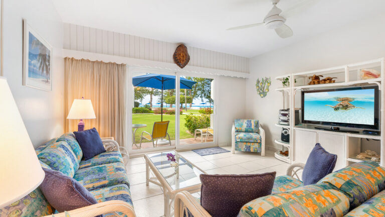 The living room of first floor Villa 3, Grand Cayman Condo Rental with a view of the grounds and beach.